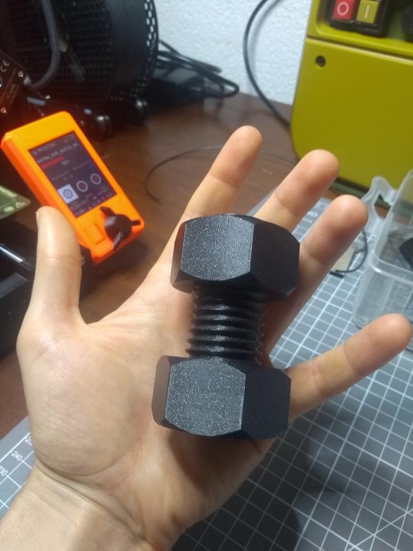 A big 3D-printed screw, placed on a hand for size comparison.